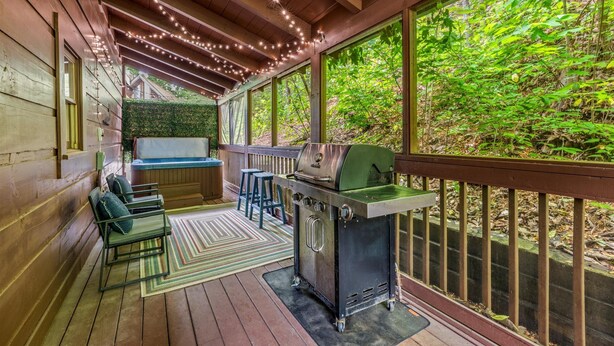 Un espace extérieur abrité, équipé d’un barbecue, de sièges et de guirlandes lumineuses.