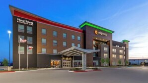 Een modern hotel met Hawthorn Extended Stay en La Quinta branding, met een opvallende ingang en een overdekte doorgang.