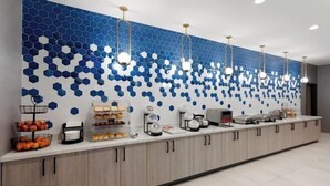Een moderne receptie met een balie, manden met fruit en een wand met een blauw-wit honingraatpatroon.