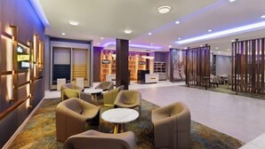 Een moderne lobby met zithoeken, een receptiebalie en een decoratieve scheidingswand.