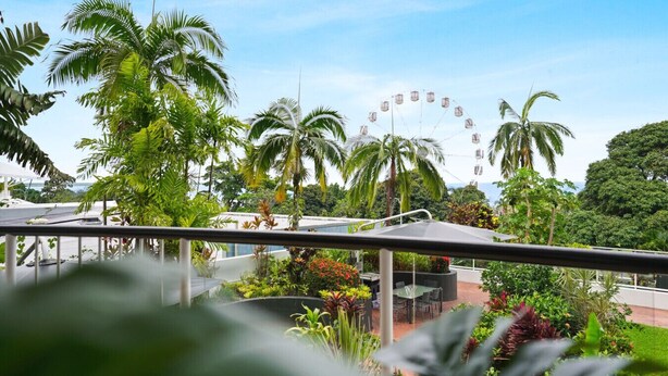 A tropical resort with a Ferris wheel, palm trees, and a pool area. - Charming 1-Bedroom Apartment with Rooftop Pool & Prime Cairns Location (Cairns City)