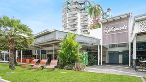 A hotel with a modern design, featuring a prominent 'Harbour Resort' sign, a covered outdoor seating area, and a well-maintained garden with palm trees. - Charming 1-Bedroom Apartment with Rooftop Pool & Prime Cairns Location (Cairns City)