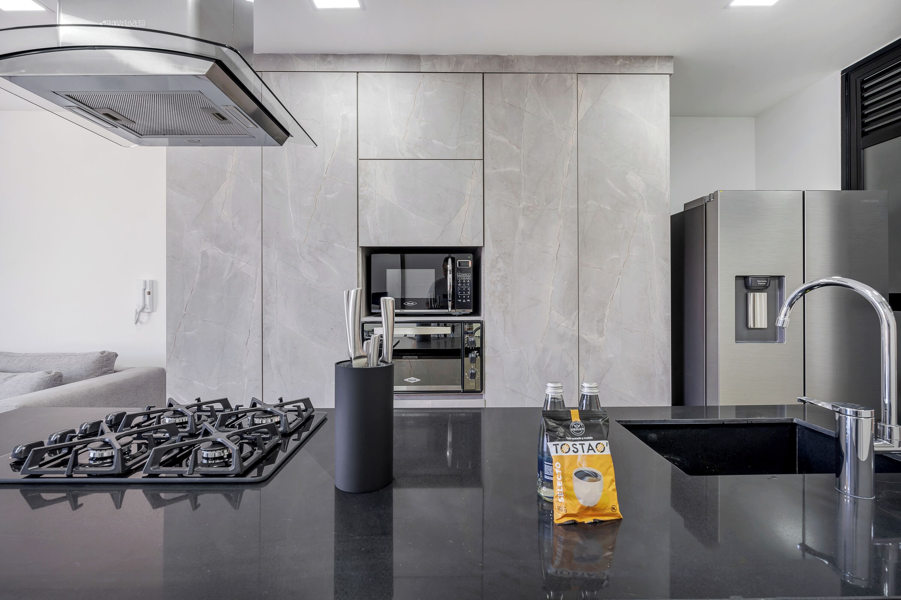 Een moderne keuken met een gasfornuis, een koffieapparaat en een waterdispenser.