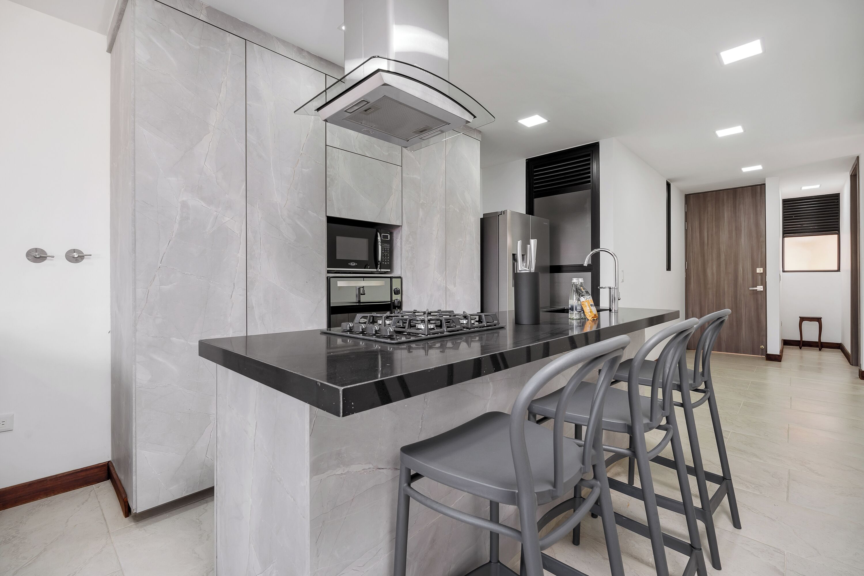 Una cocina moderna con encimera de mármol, electrodomésticos de acero inoxidable y una zona de bar con taburetes.