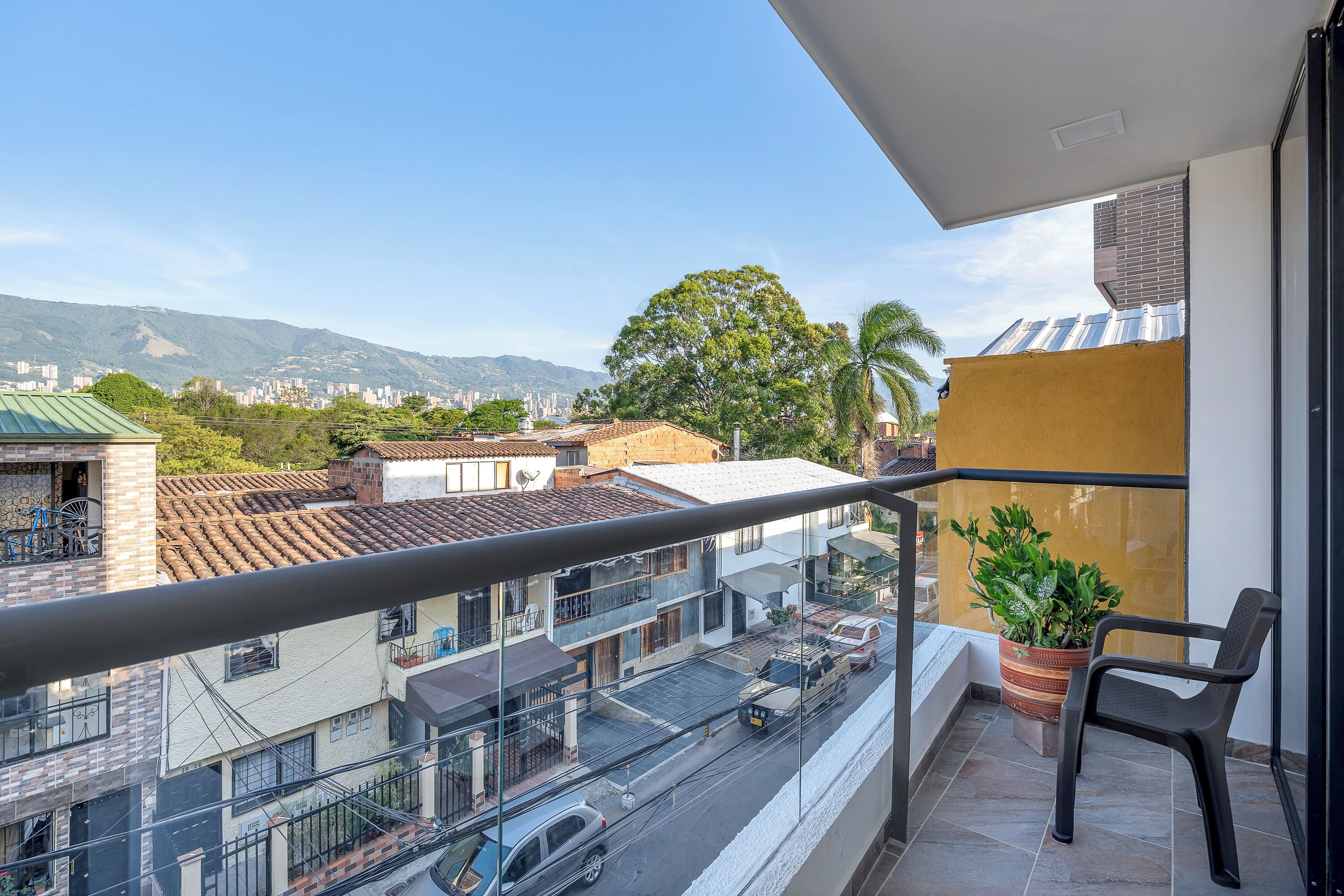 Un balcón con vista a un paisaje urbano, que incluye edificios y montañas.