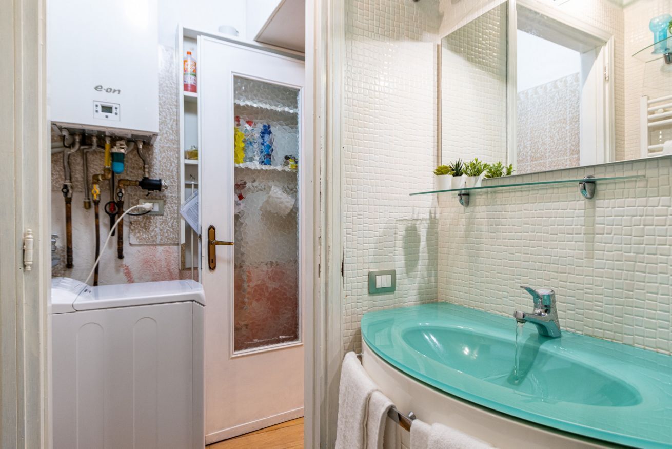 A bathroom with a glass sink, a white radiator, and a shower area.