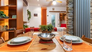 A dining area with a wooden table set for two, a decorative metal bowl centerpiece, and a red upholstered sofa in the background. - [Verbania-Suna] Love Nest Apartment - 50m from the lake - Free Wi-Fi (Verbania)