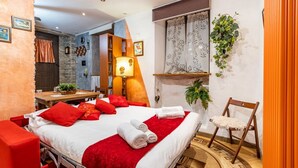 A hotel room with a bed, a desk, a chair, a window with curtains, and a wall-mounted plant. - [Verbania-Suna] Love Nest Apartment - 50m from the lake - Free Wi-Fi (Verbania)