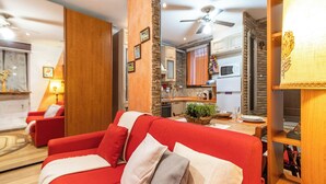 A modern living room with a red sofa, a wooden accent wall, and a kitchen in the background. - [Verbania-Suna] Love Nest Apartment - 50m from the lake - Free Wi-Fi (Verbania)