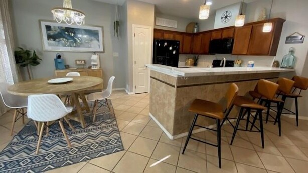 Una cocina moderna con armarios de madera, una isla central con taburetes y una zona de comedor con una mesa redonda y sillas.