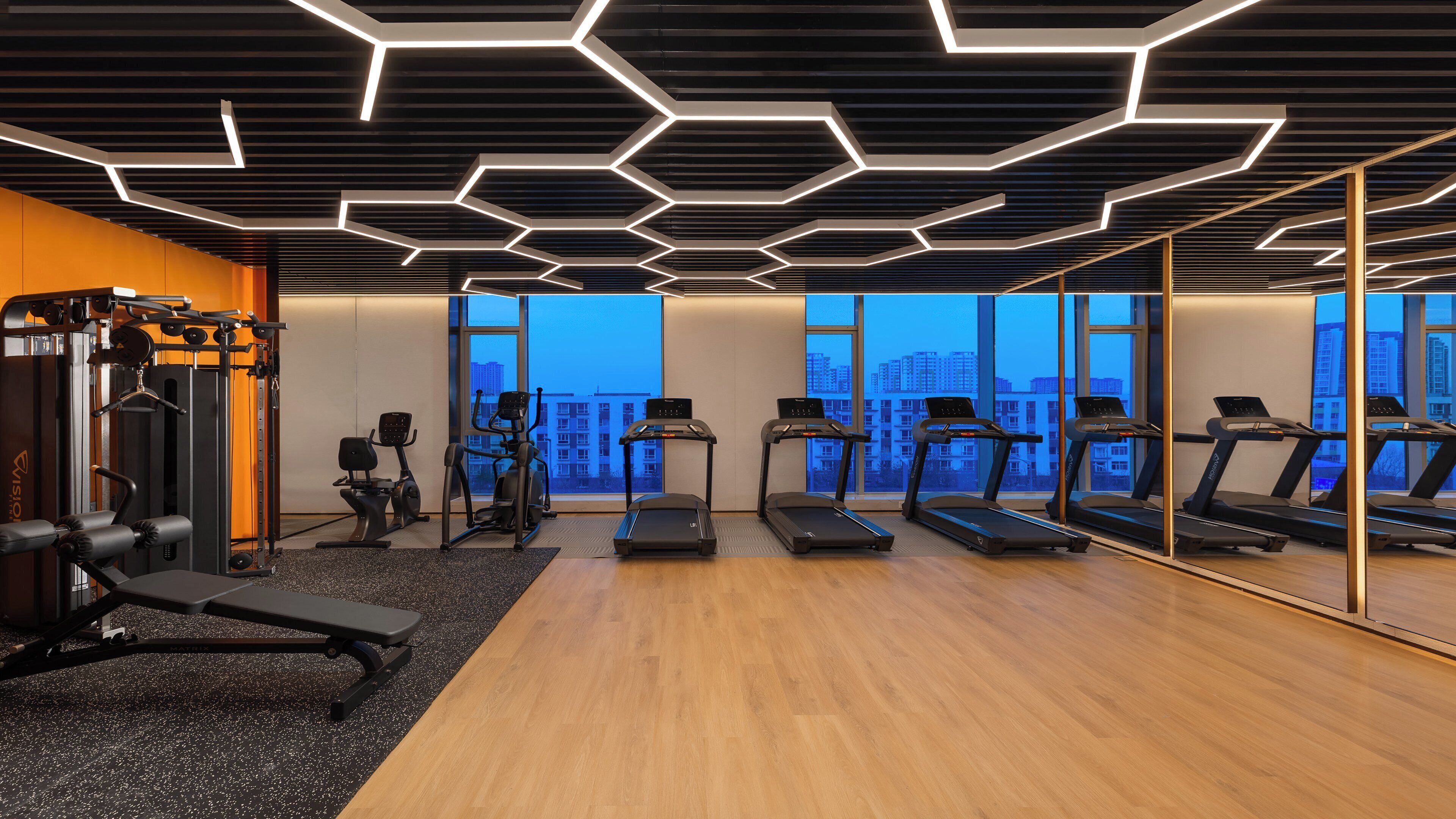 Un gimnasio moderno con cintas de correr, elípticas y equipo de levantamiento de pesas.