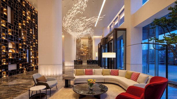 A modern lobby with a curved sofa, a coffee table, and a reception desk. - Holiday Inn Datong by IHG (Datong)