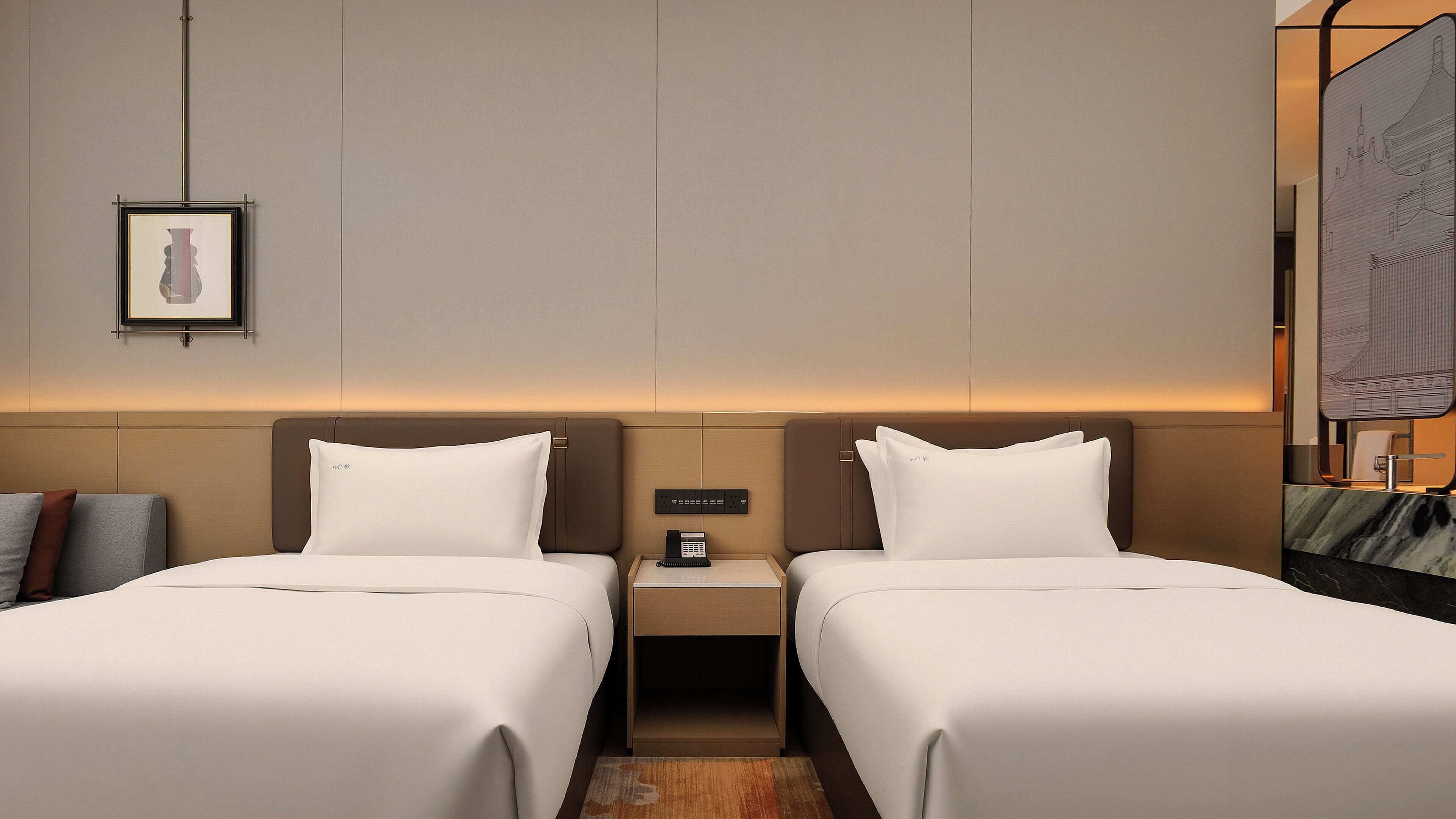 A hotel room with two beds, a nightstand with a phone, and a framed picture on the wall.