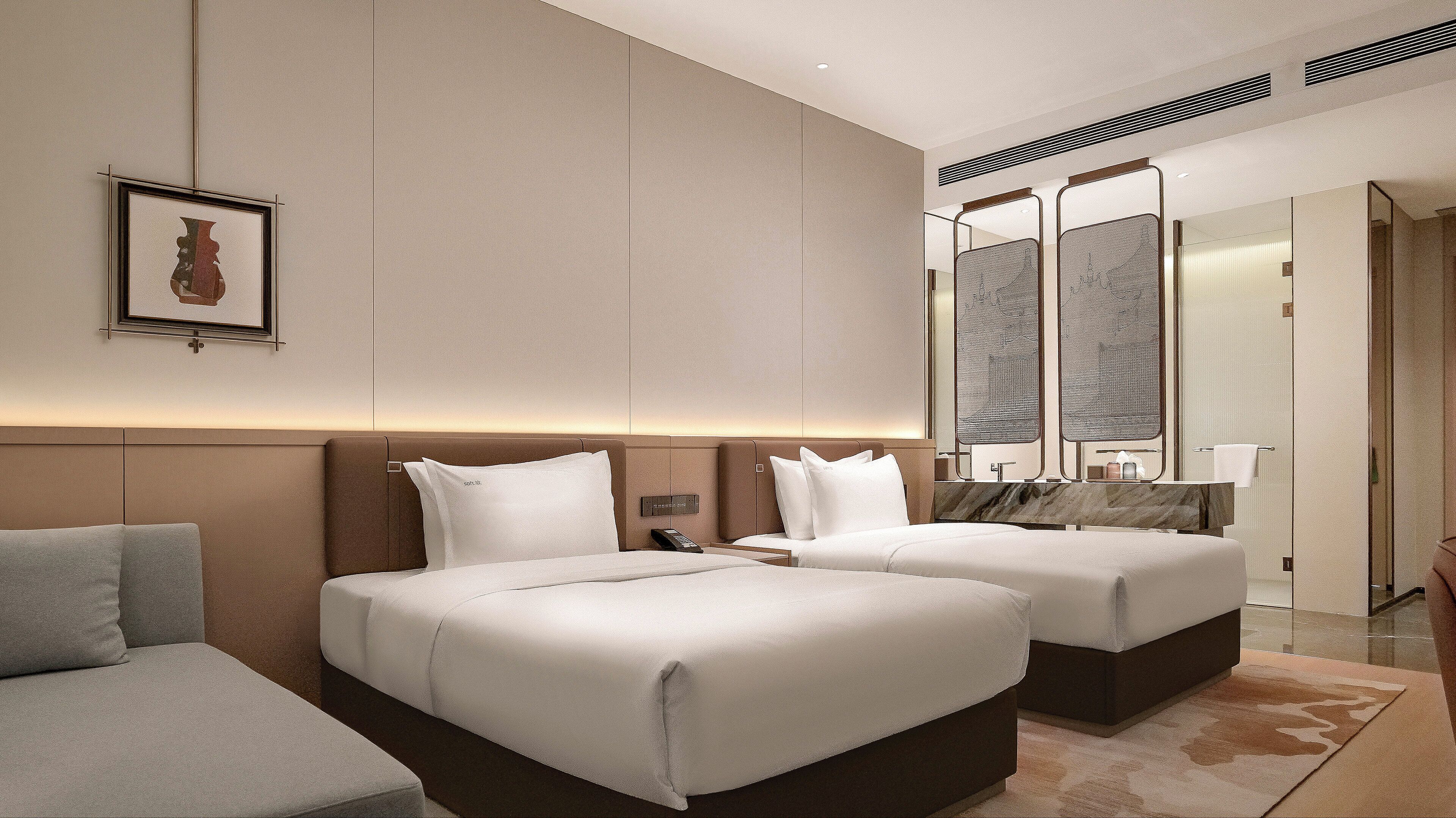 A hotel room with two beds, a sitting area, a large mirror, and a framed picture on the wall.