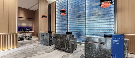 A modern reception area with marble counters, a blue patterned wall, and pendant lighting.