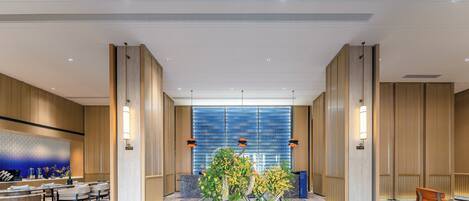A modern lobby with a marble reception desk, seating area, and a central floral arrangement.