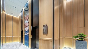 A modern elevator interior with a directory sign, a potted plant, and a marble floor. - Holiday Inn Express Haikou World Trade Center by IHG (Haikou)