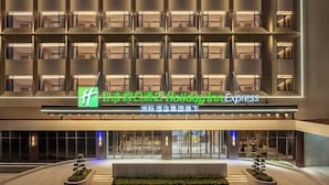 A hotel entrance with a modern facade, multiple balconies, and a sign indicating it is part of the Holiday Inn Express brand. - Holiday Inn Express Haikou World Trade Center by IHG (Haikou)