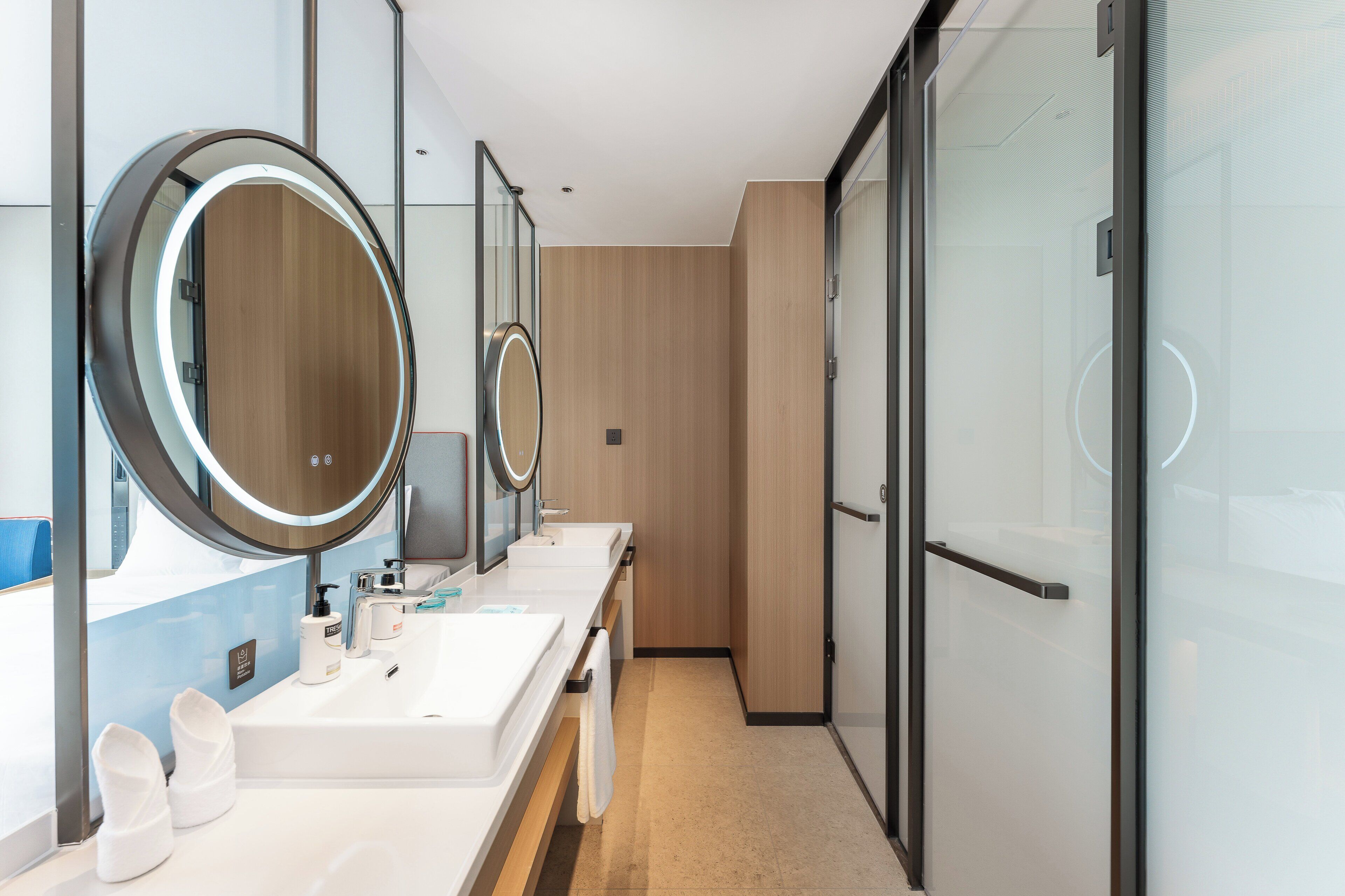 A modern bathroom with two sinks, large mirrors, and a wooden panel wall.