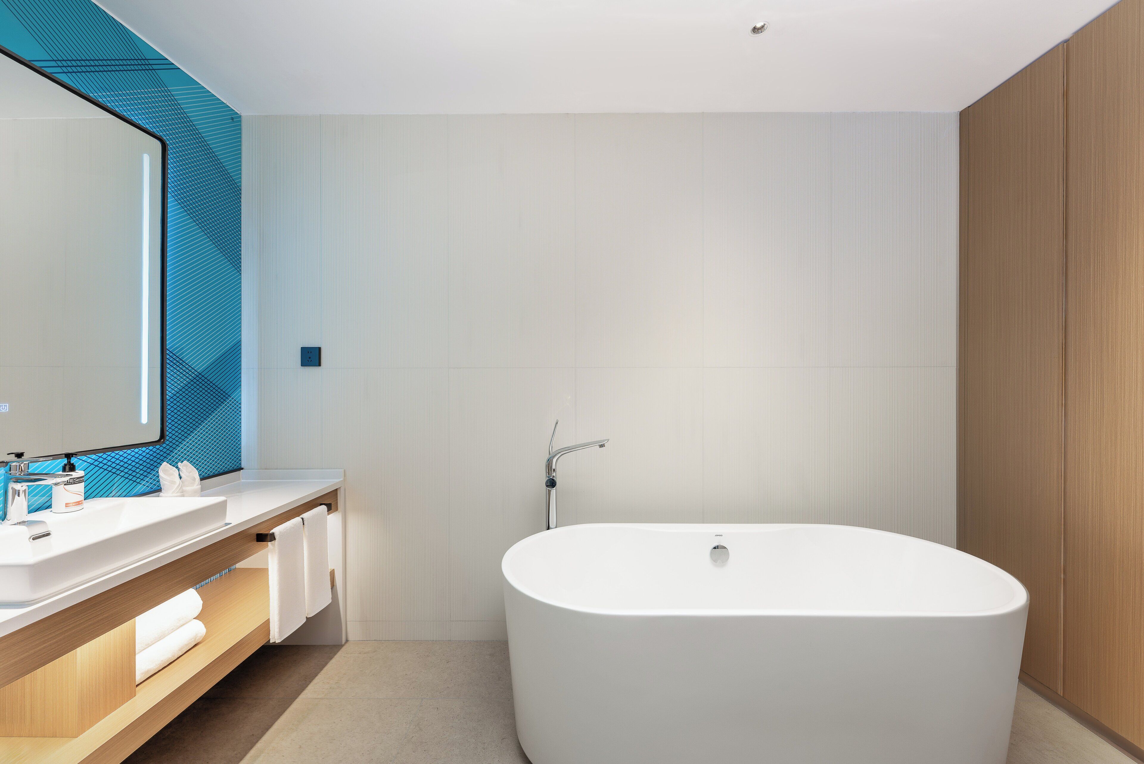 A modern bathroom with a freestanding bathtub, two sinks, and a large mirror.