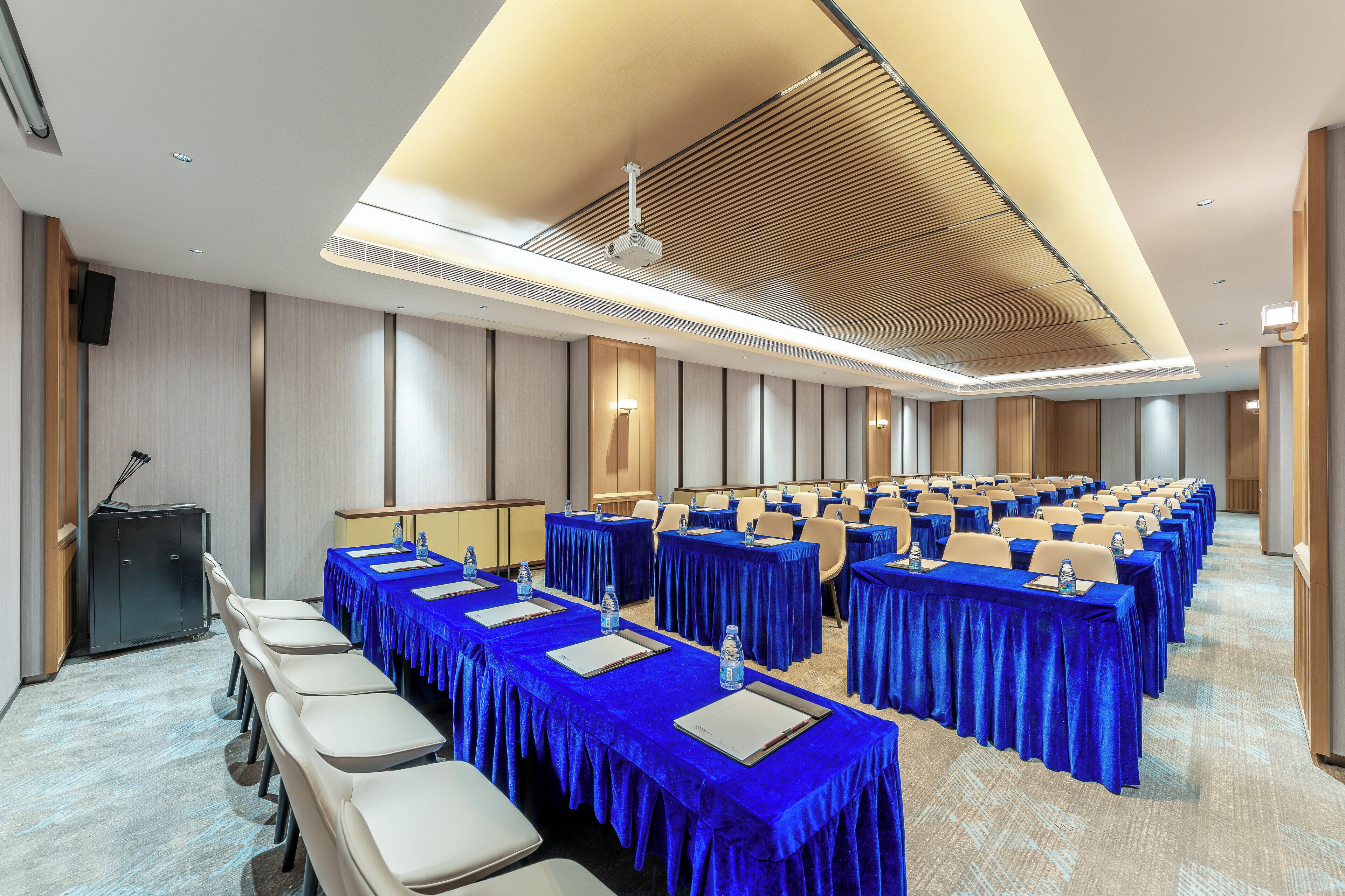 A conference room with rows of tables and chairs, equipped with water bottles and nameplates.