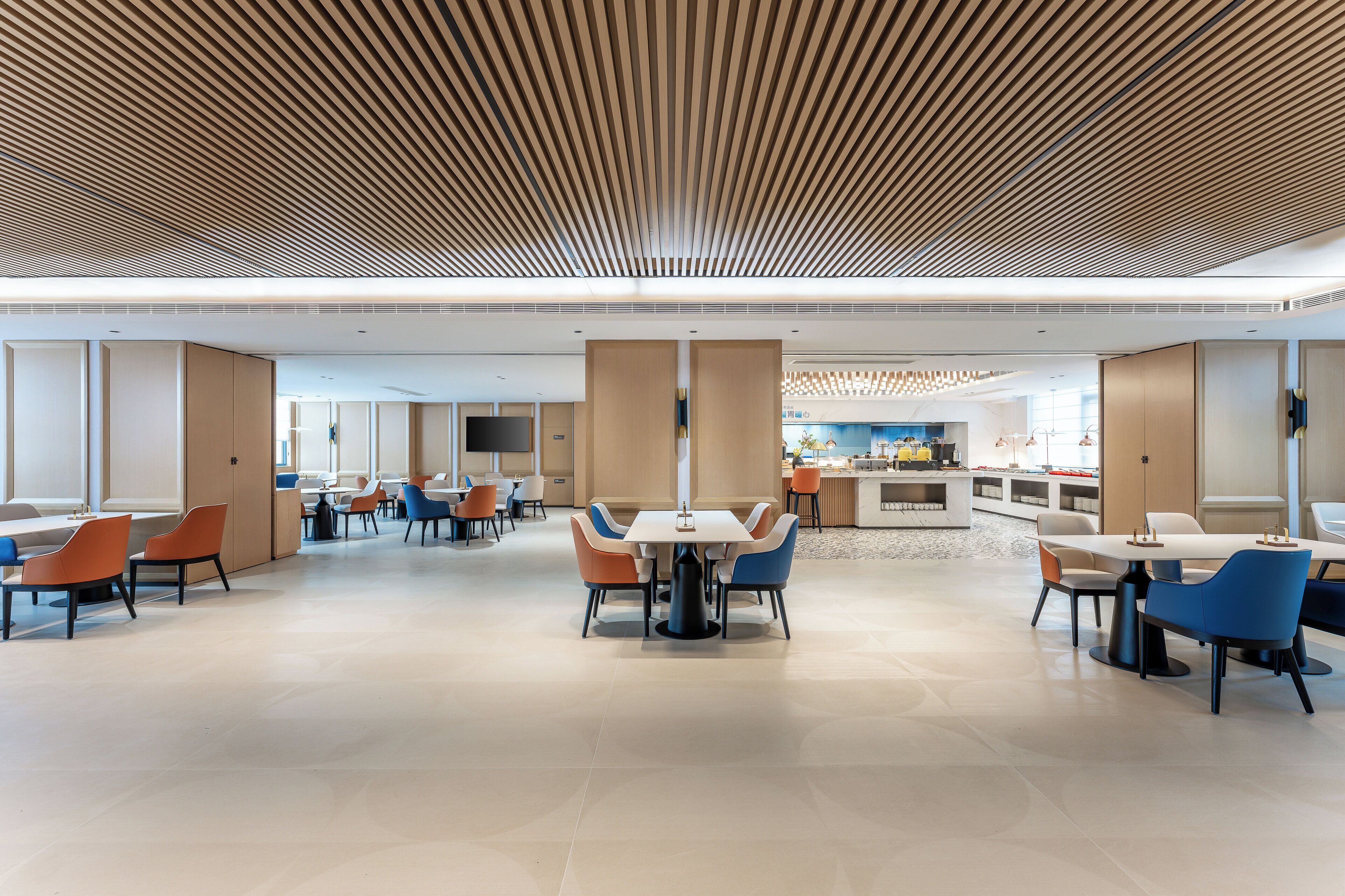A spacious, modern dining area with multiple tables and chairs, a central island, and a kitchen in the background.
