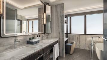 A modern bathroom with a large mirror, a bathtub, and a shower.