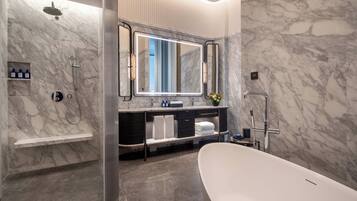 A modern bathroom with a freestanding bathtub, a large mirror, and marble walls.