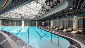 An indoor swimming pool with a modern design, featuring a geometric ceiling structure and a seating area with loungers along the poolside. - Intercontinental Hangzhou Wulin by IHG (Hangzhou)