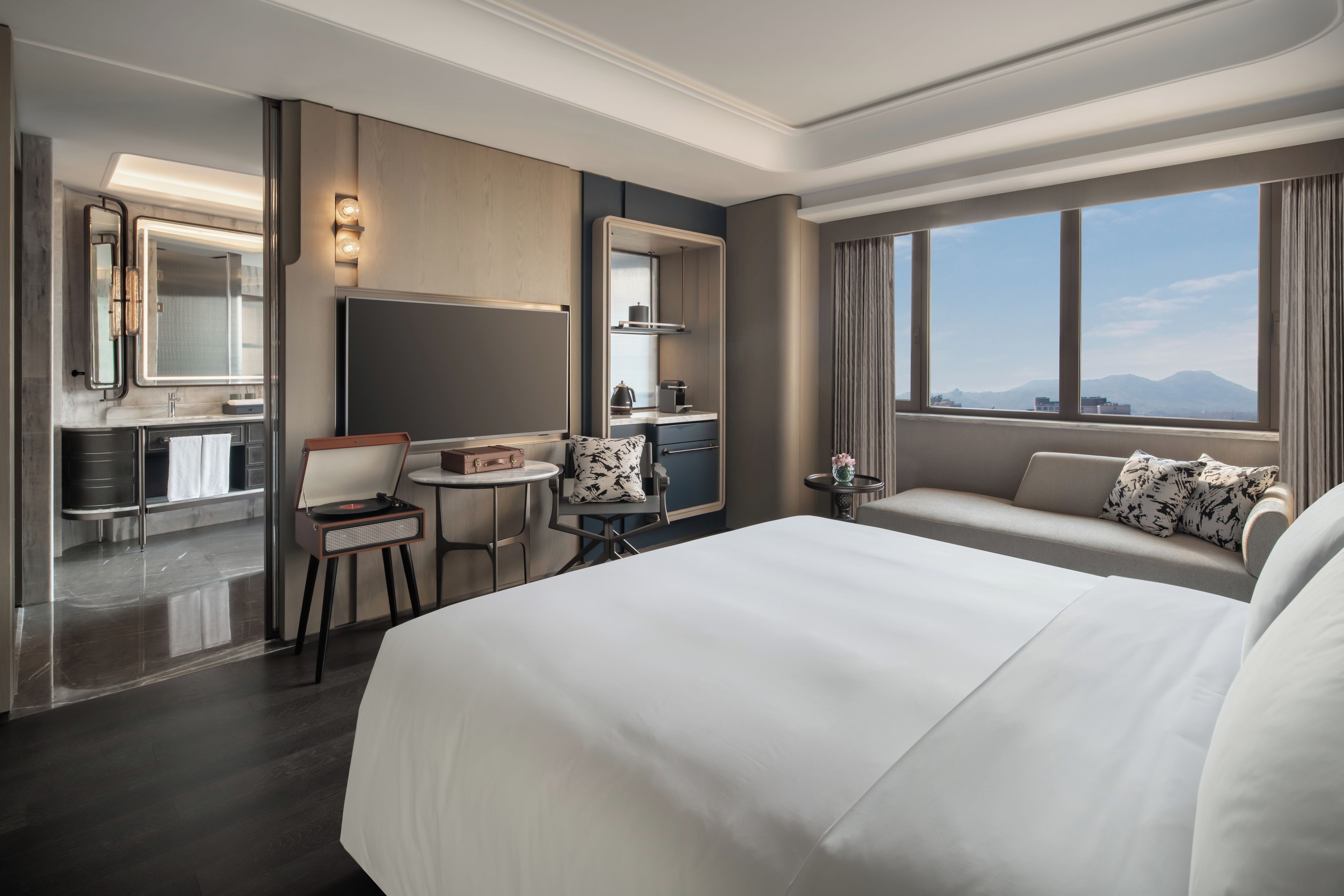 Una habitación de hotel con una cama grande, un escritorio con una silla, una mesita pequeña y un sofá.