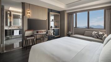 Una habitación de hotel con una cama grande, un escritorio con una silla, una mesita pequeña y un sofá.