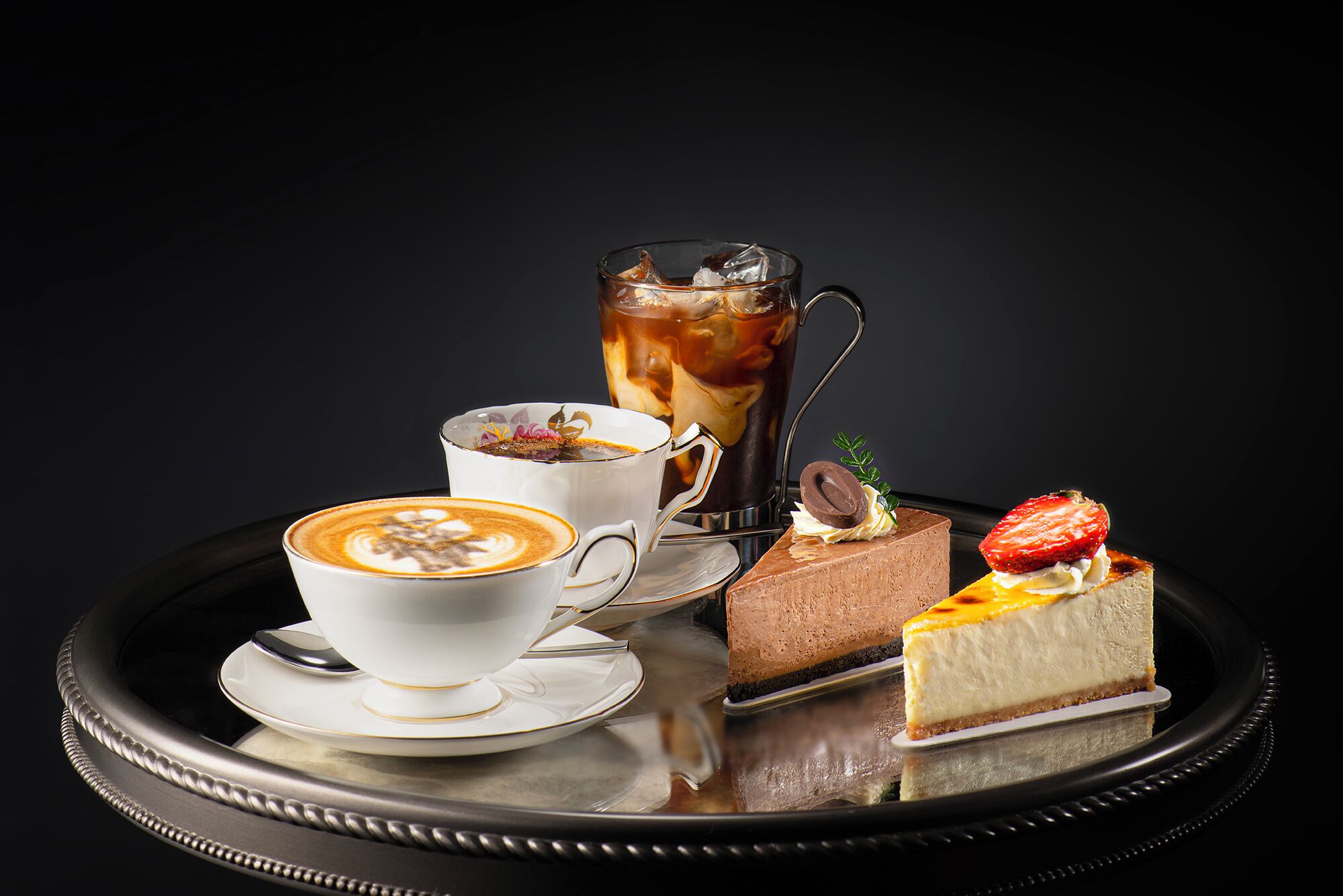 Una bandeja con una taza de café, una jarra de café helado y dos postres.