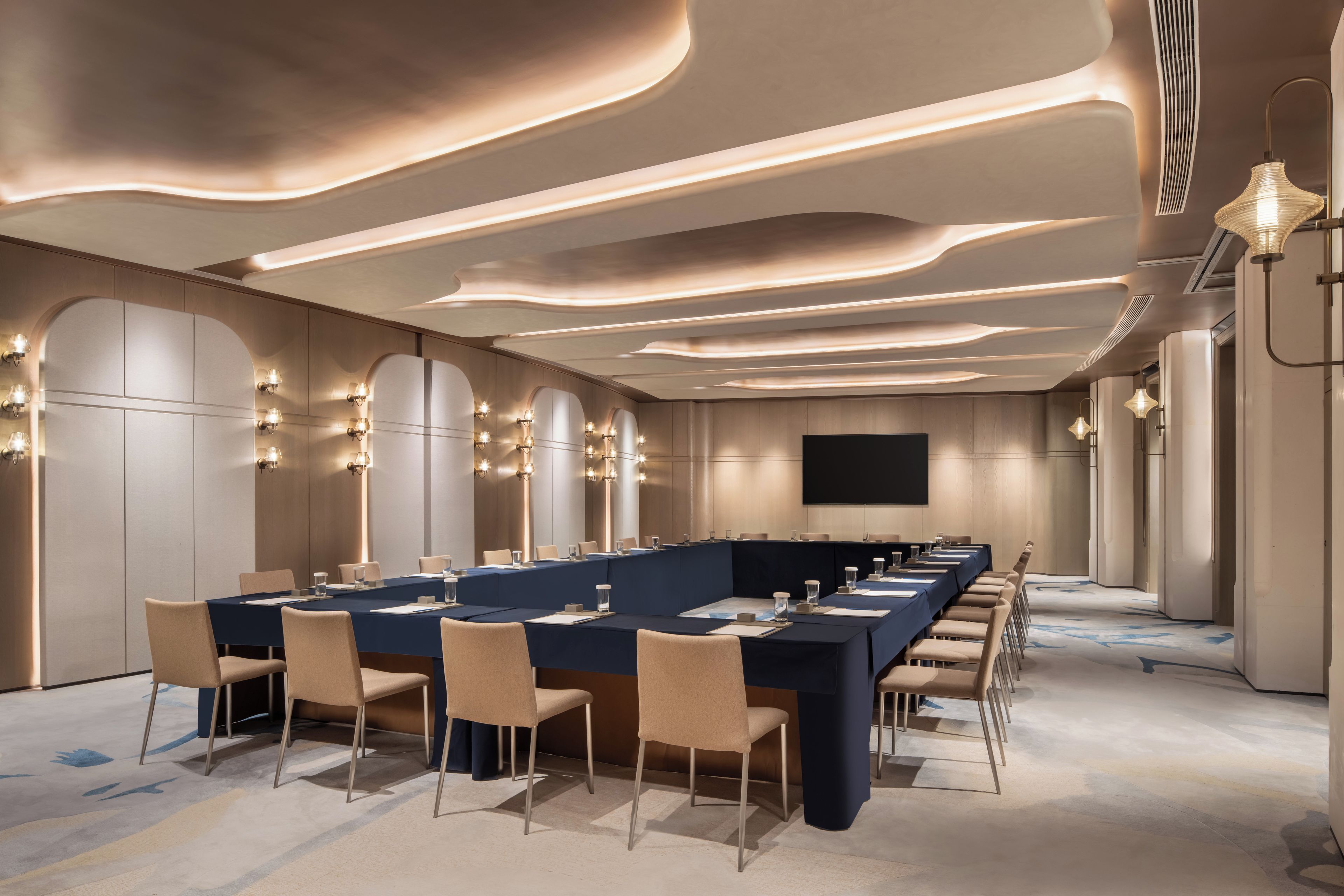 A conference room with a long table, chairs, and a flat-screen TV.
