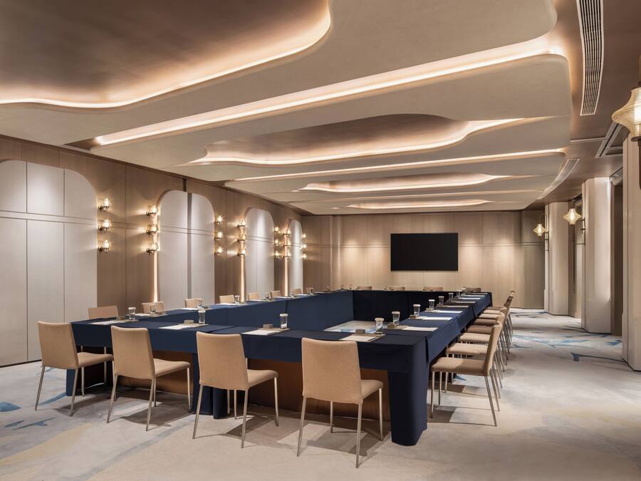 A conference room with a long table, chairs, and a flat-screen TV.