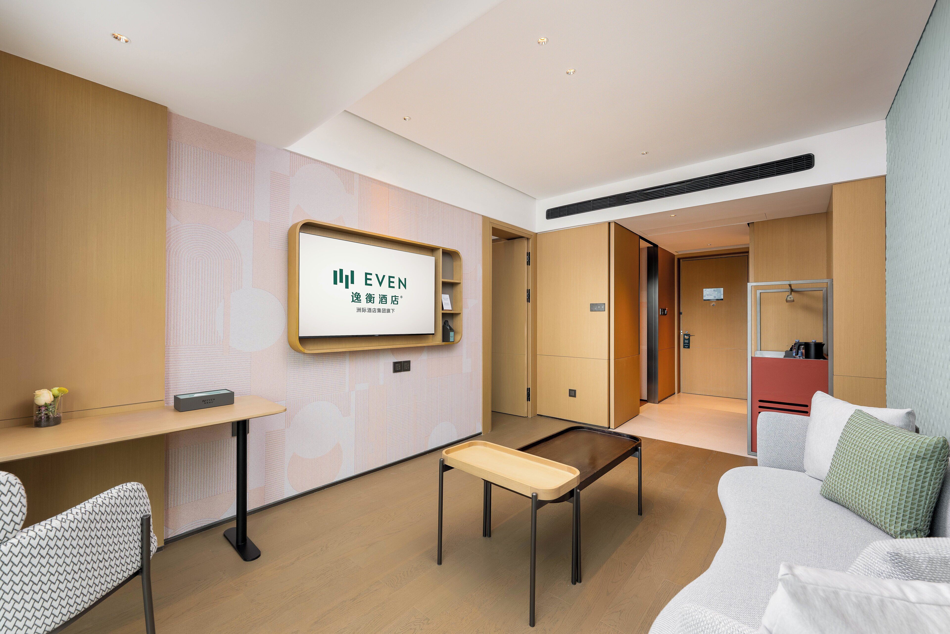 Un hall d’hôtel moderne avec un comptoir d’accueil, un espace salon et une enseigne indiquant le nom de l’hôtel : « EVEN ».