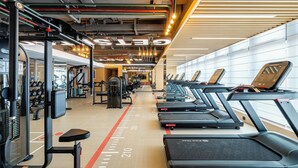 Un gimnasio con cintas de correr, máquinas de pesas y una variedad de equipos de ejercicio.