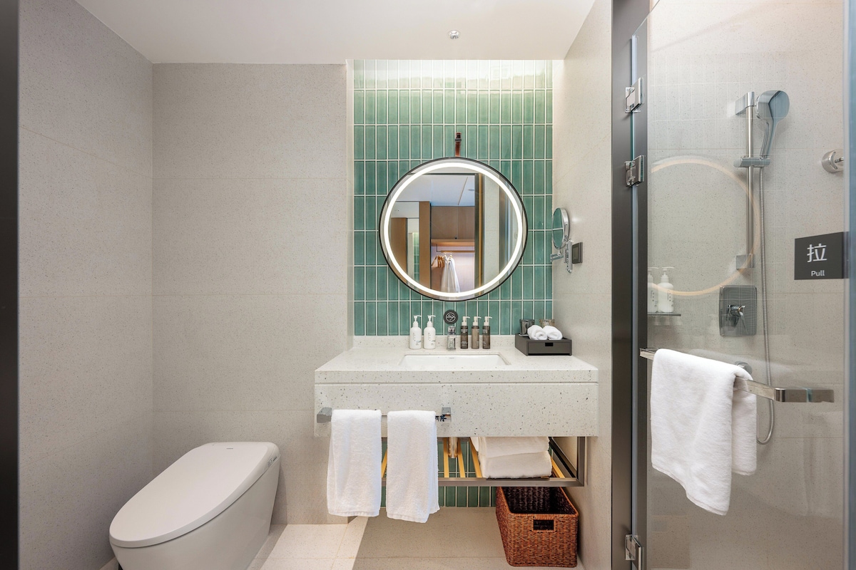 A bathroom with a toilet, sink, mirror, and shower.