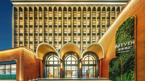 Un hotel con fachada moderna, varios balcones y una entrada destacada con arcos.