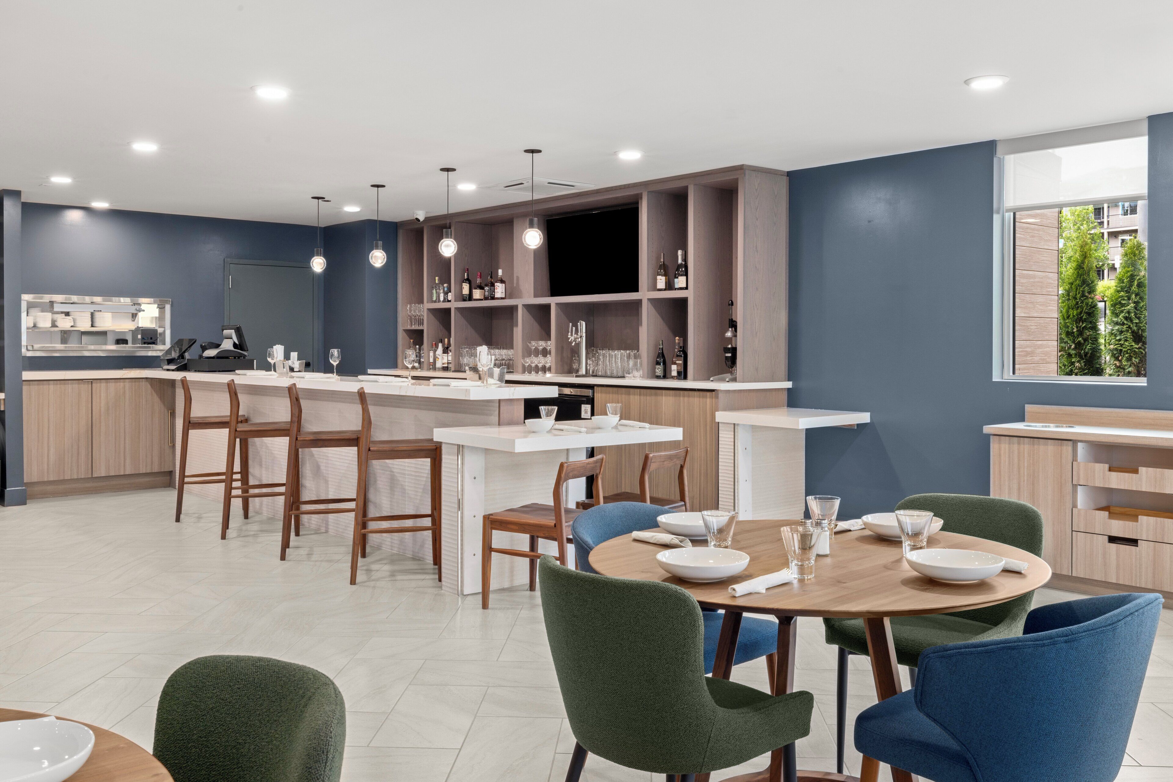 Una cocina moderna con comedor, que cuenta con una isla central, barra y estanterías empotradas.