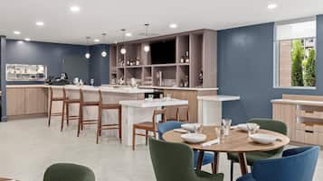 Una cocina moderna con comedor, que cuenta con una isla central, barra y estanterías empotradas.