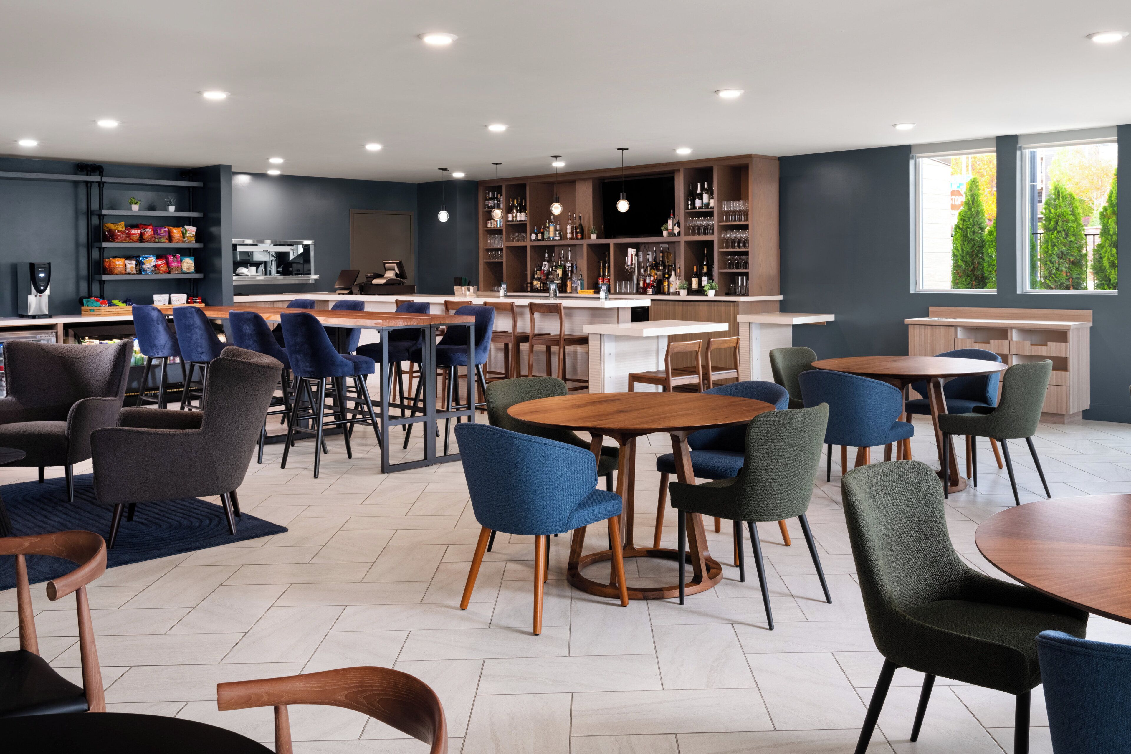 A modern bar area with multiple seating options, including round tables and bar stools, and a variety of seating arrangements.