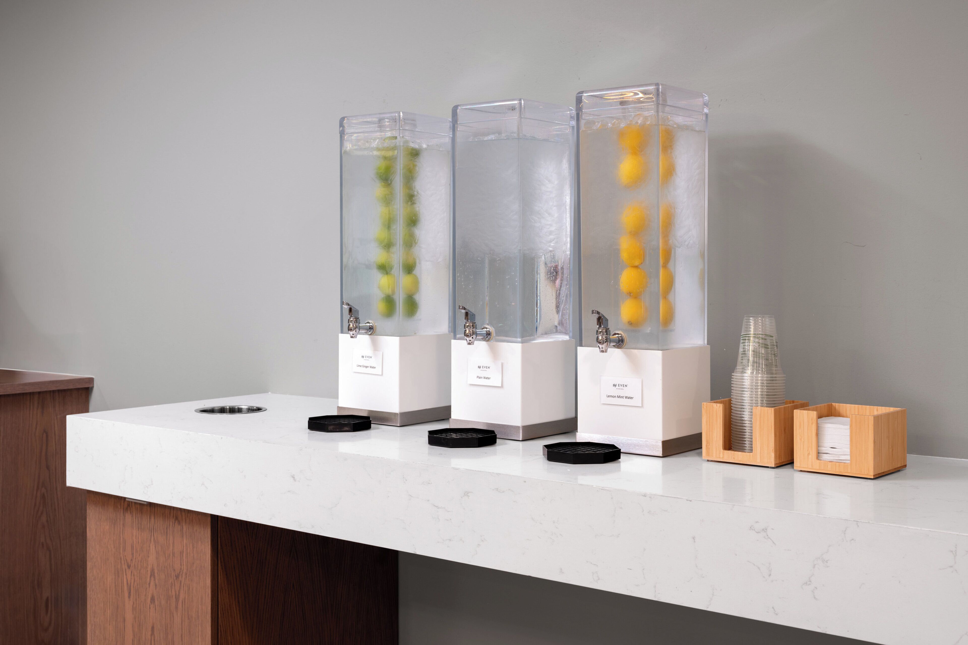 Three water dispensers on a white countertop, each labeled with different water types.