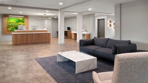 A modern reception area with a wooden desk, a grey sofa, and a marble coffee table. - EVEN Hotel Portland – Beaverton by IHG (Portland)