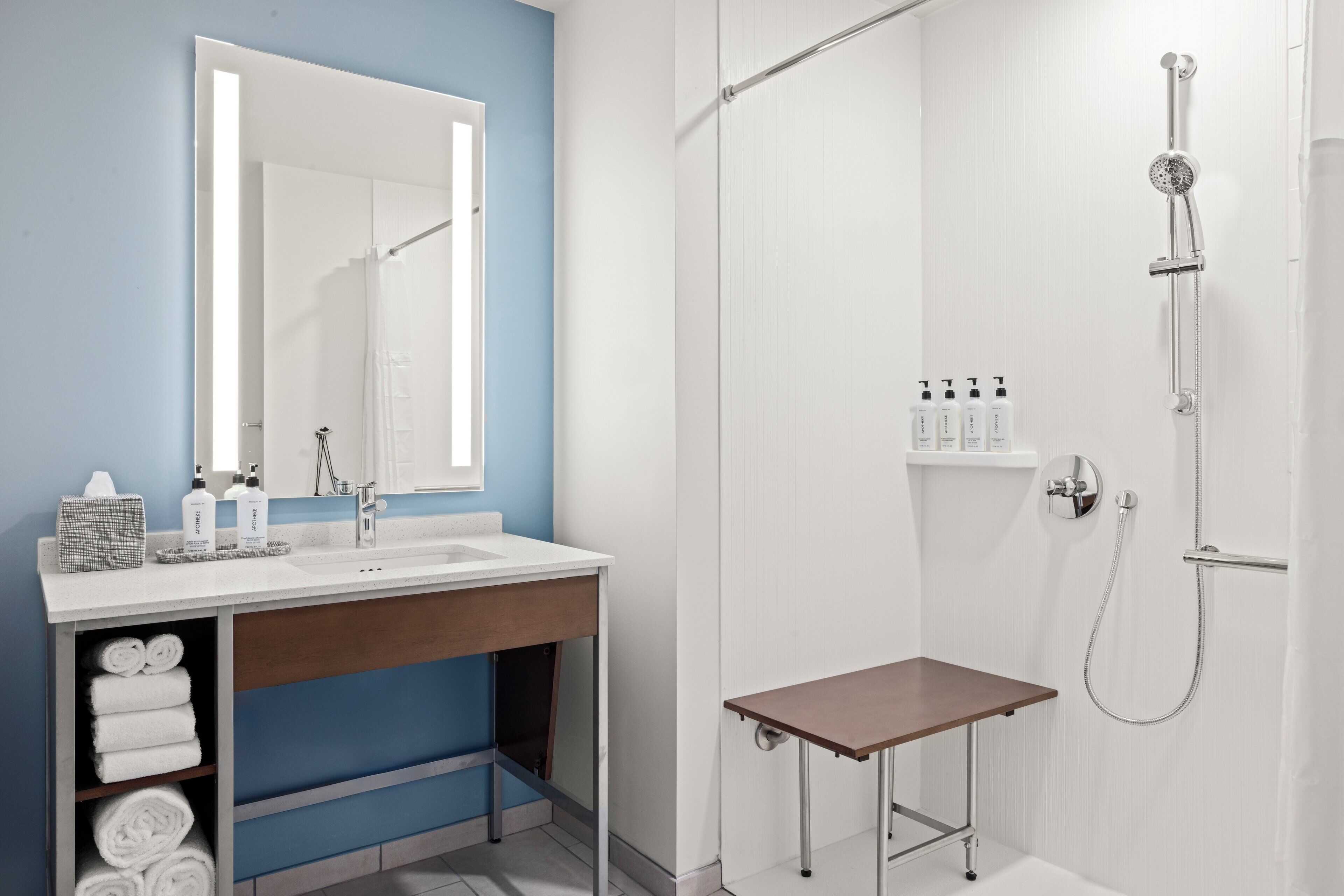 A modern bathroom with a white vanity, a large mirror, and a shower area.