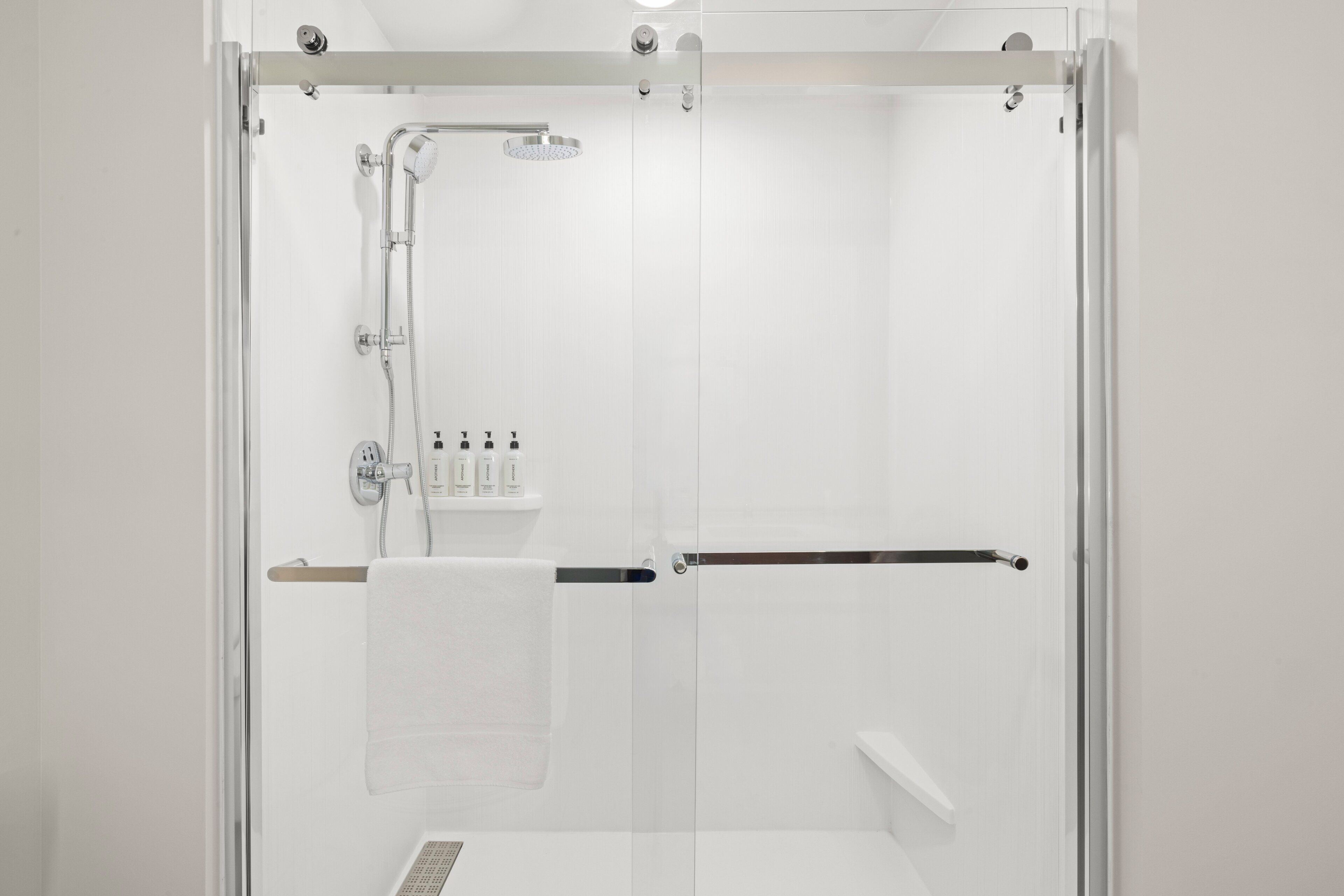 Eine moderne Duschkabine mit Glastür, Handbrause und einer Bedienkonsole mit mehreren Armaturen.