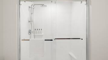Eine moderne Duschkabine mit Glastür, Handbrause und einer Bedienkonsole mit mehreren Armaturen.