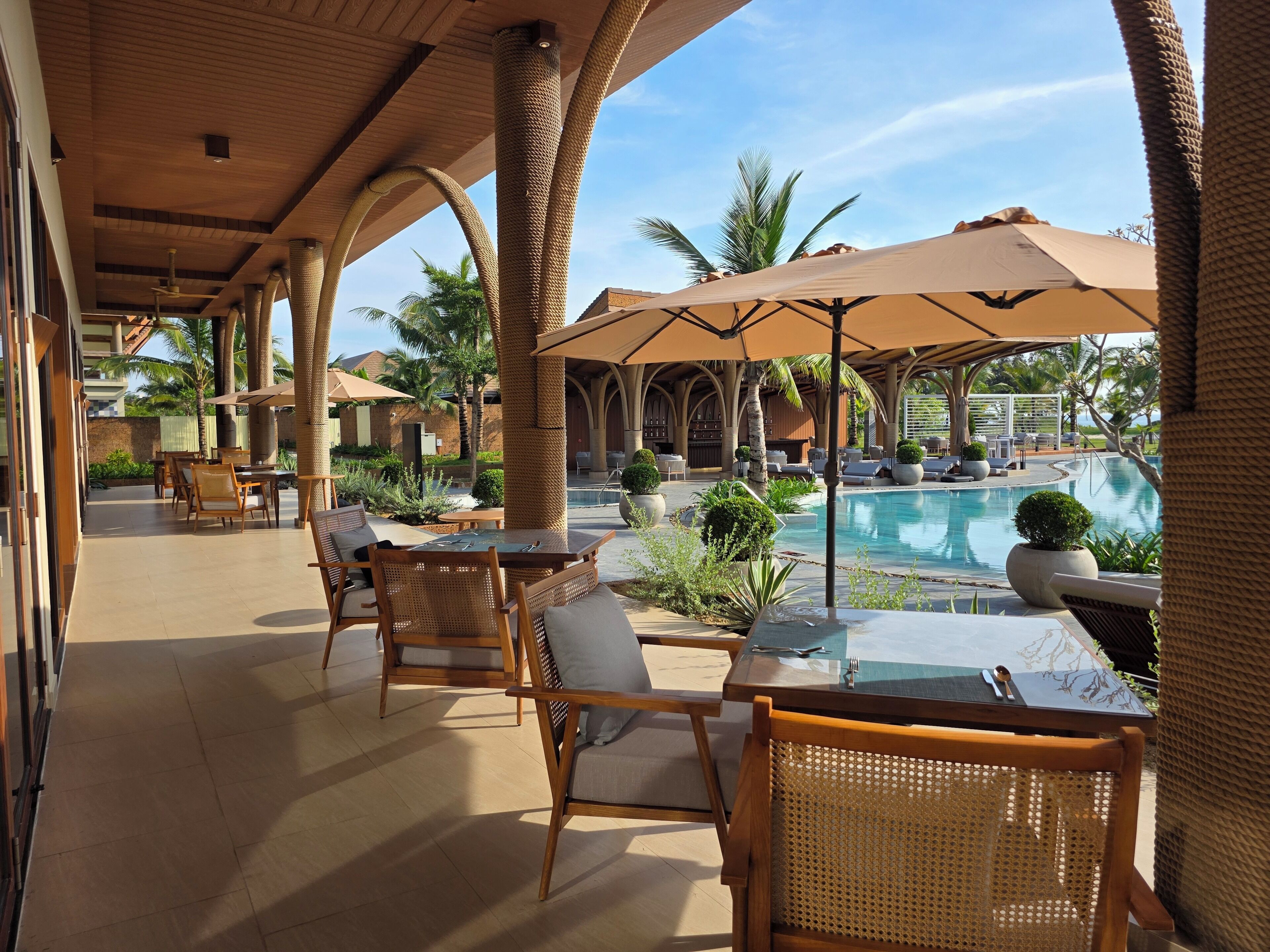 A poolside area with wicker furniture, umbrellas, and a view of the pool.