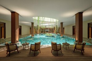 A pool area with a circular water feature, wooden pillars, and wicker chairs. - voco Quang Binh Resort by IHG (Dong Hoi)