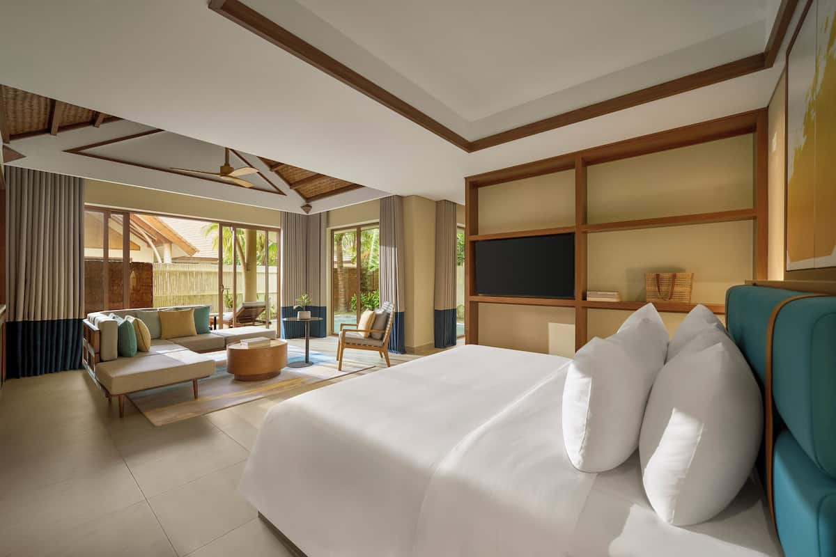 Ein modernes Hotelzimmer mit einem großen Bett, einem Sofa, einem Sessel und einem kleinen Tisch.