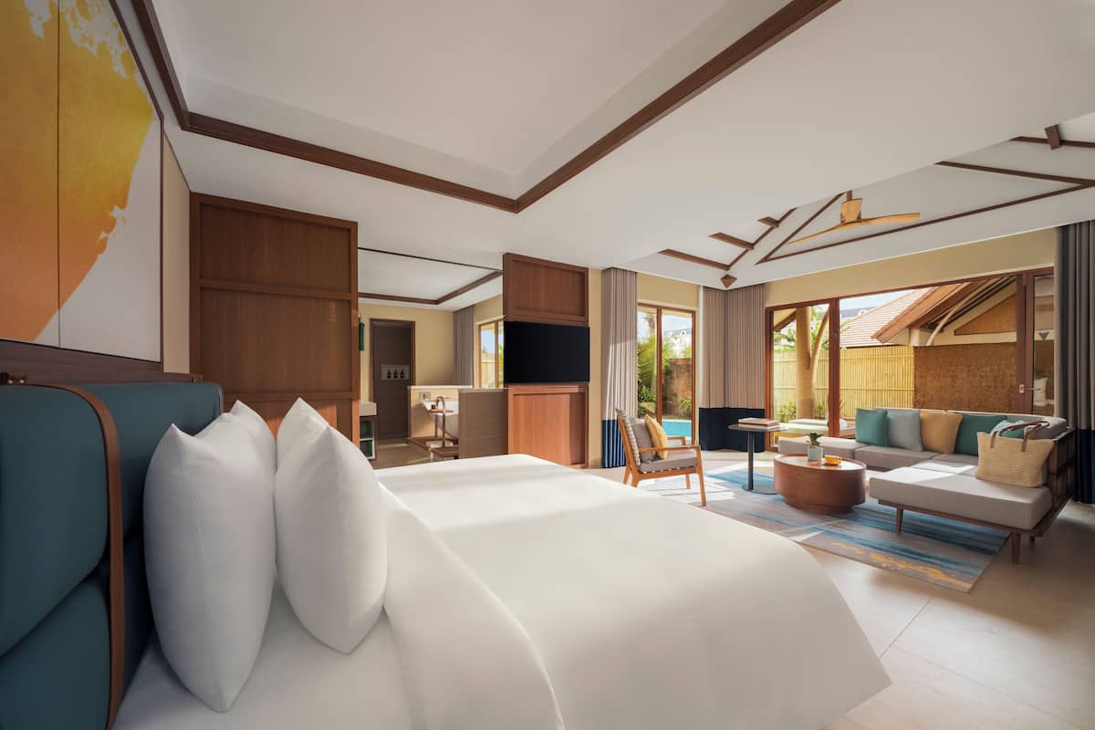 Ein modernes Hotelzimmer mit einem großen Bett, einer Sitzecke, einem Essbereich und einem Fernseher.
